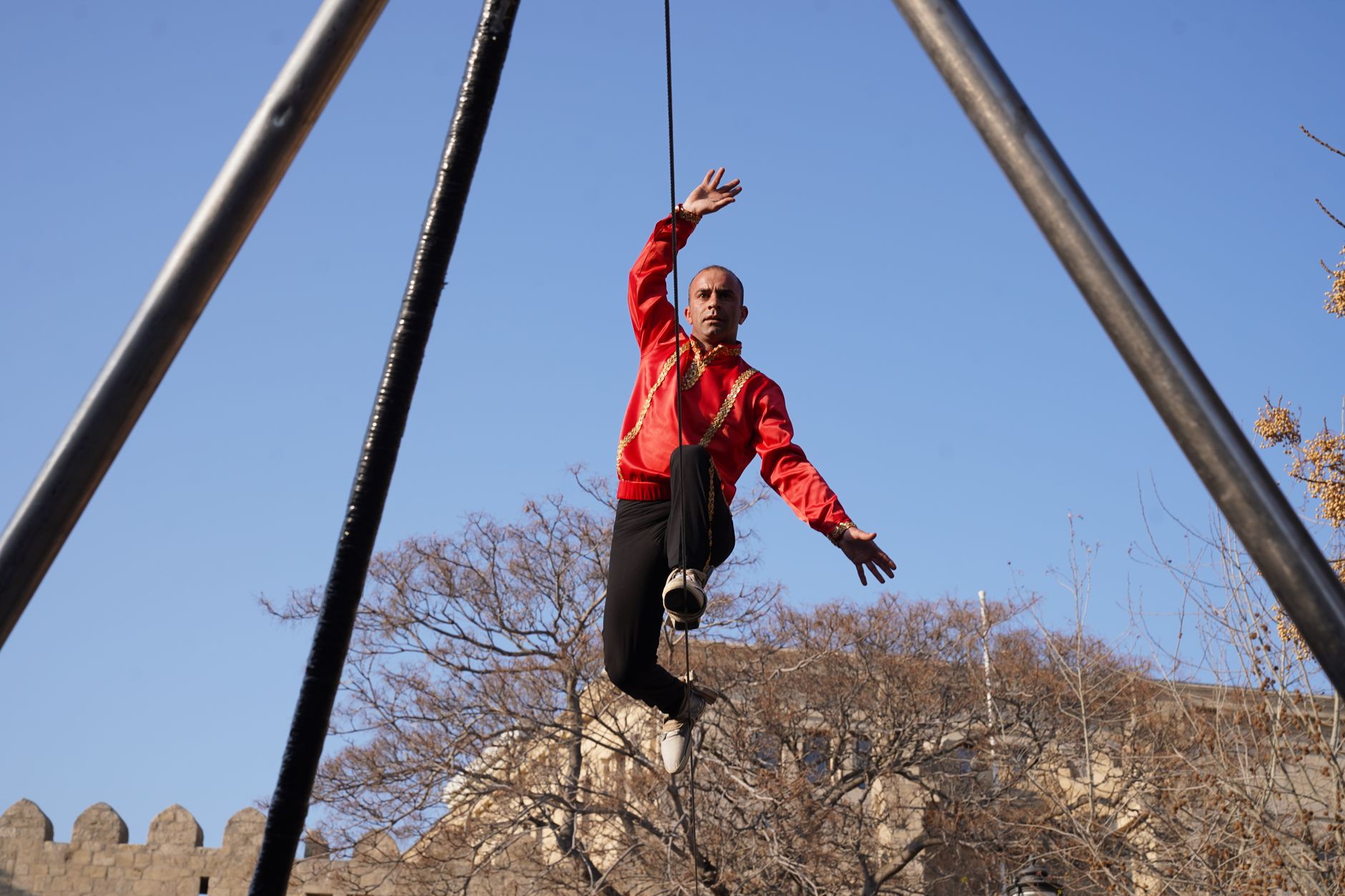 Une acrobate en haut d'un mât dressé sur une place